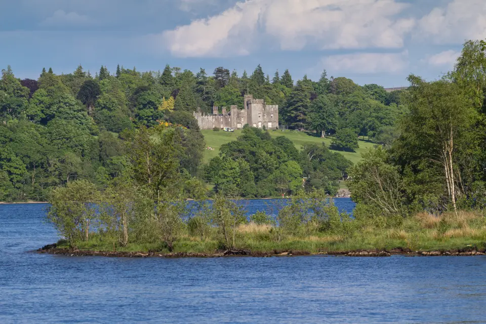 Balloch Castle among trees above the loch shore, seen across the water